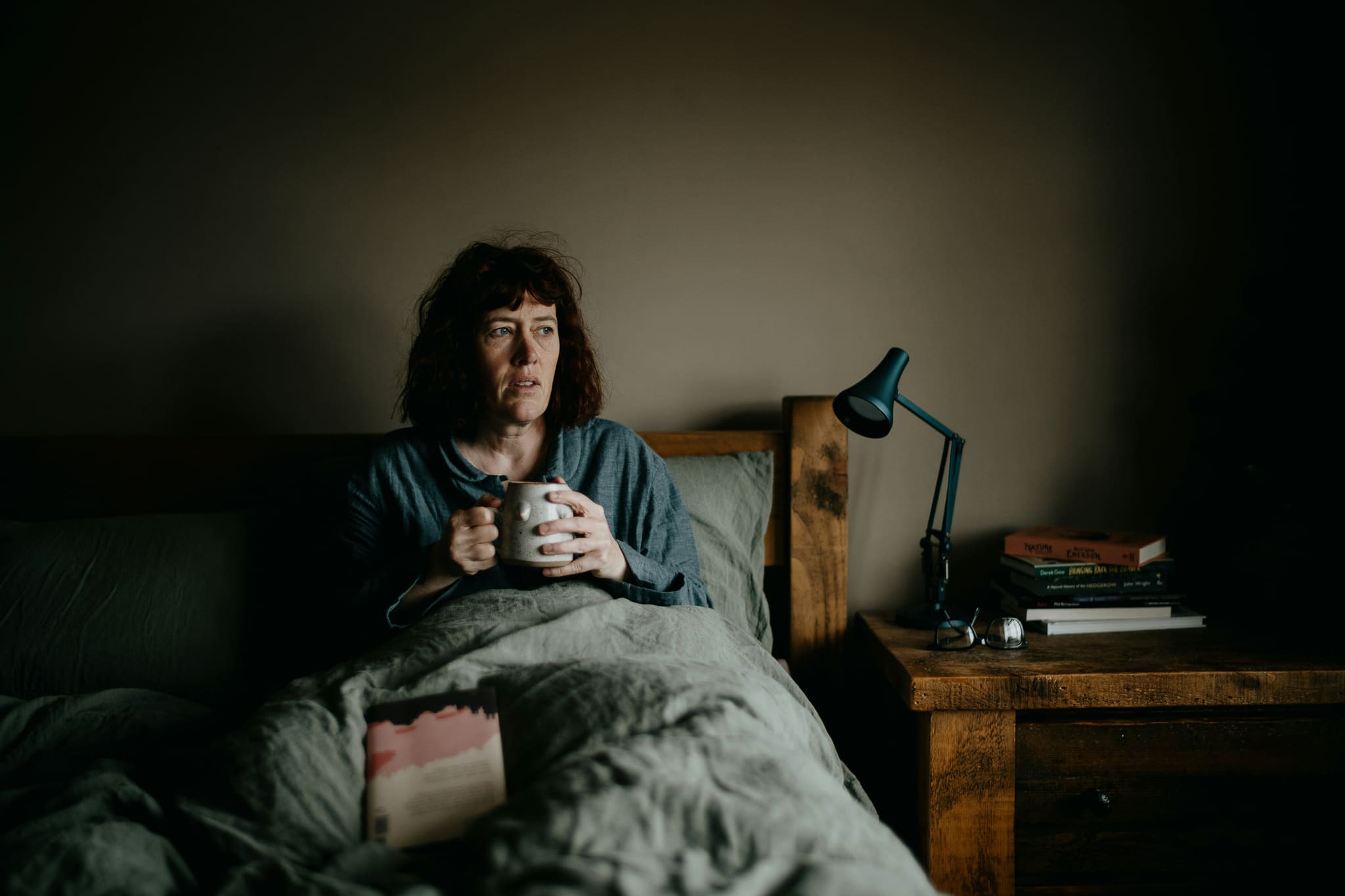 Symbolbild: Eine Frau sitzt krank im Bett und hält eine Tasse Tee.